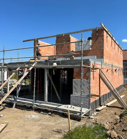 Ruwbouwfase van een nieuwbouwwoning met metselwerken en stellingen