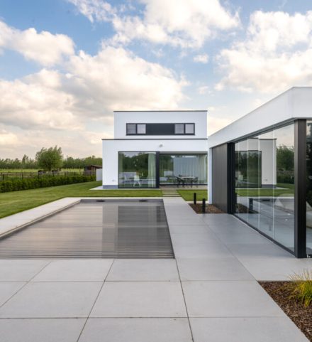 Moderne villa met grote aluminium ramen en ruime glaspartijen aan de tuinzijde.